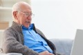 Positive elderly man using his laptop while sitting at home