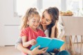 Mother and daughter reading book on the floor.